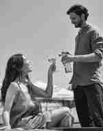 Un uomo e una donna che sorseggiano una bevanda a bordo piscina