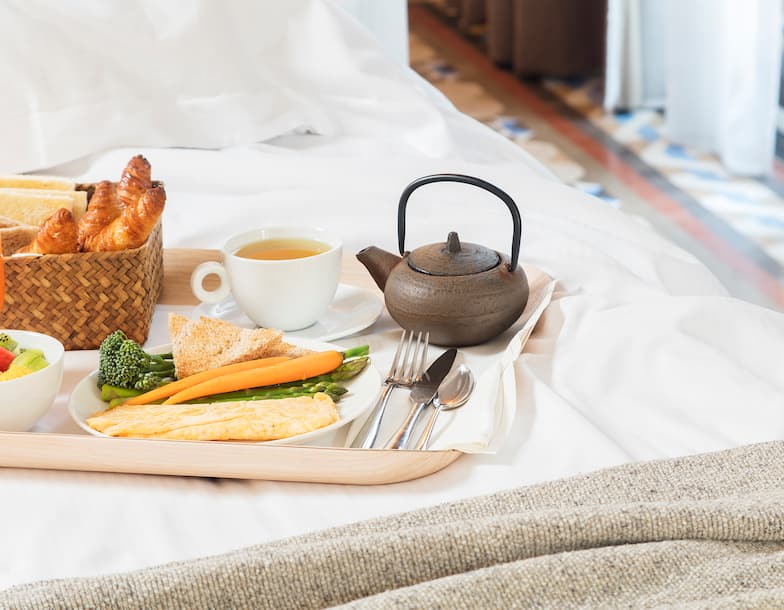 Tray with Food and Tea Drink on Bed