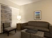 Chair, Illuminated Lamp on Side Table, Wall Art Above Soft, and Ottoman in Suite Living Room