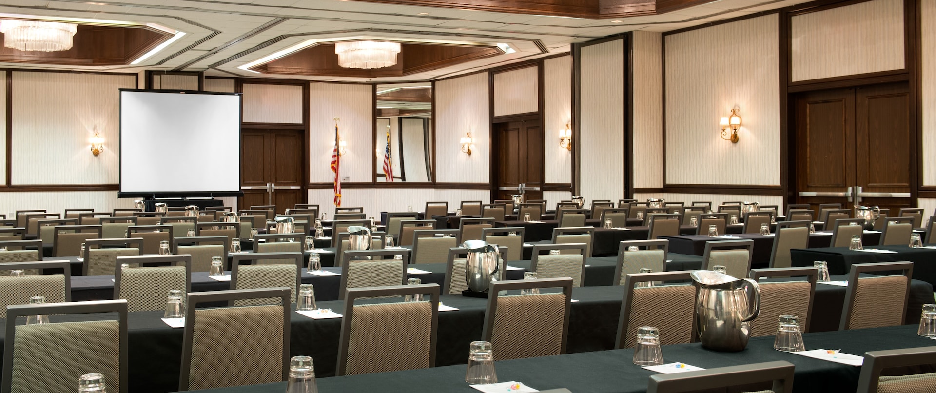 Classroom Setup in Ballroom With Tables and Chairs Facing Presentation Screen and American Flag