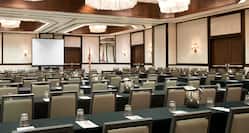 Classroom Setup in Ballroom With Tables and Chairs Facing Presentation Screen and American Flag