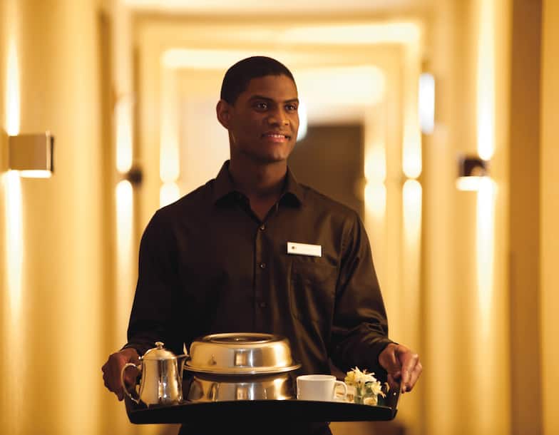 Male Waitstaff Delivering a Tray of Food From Room Service