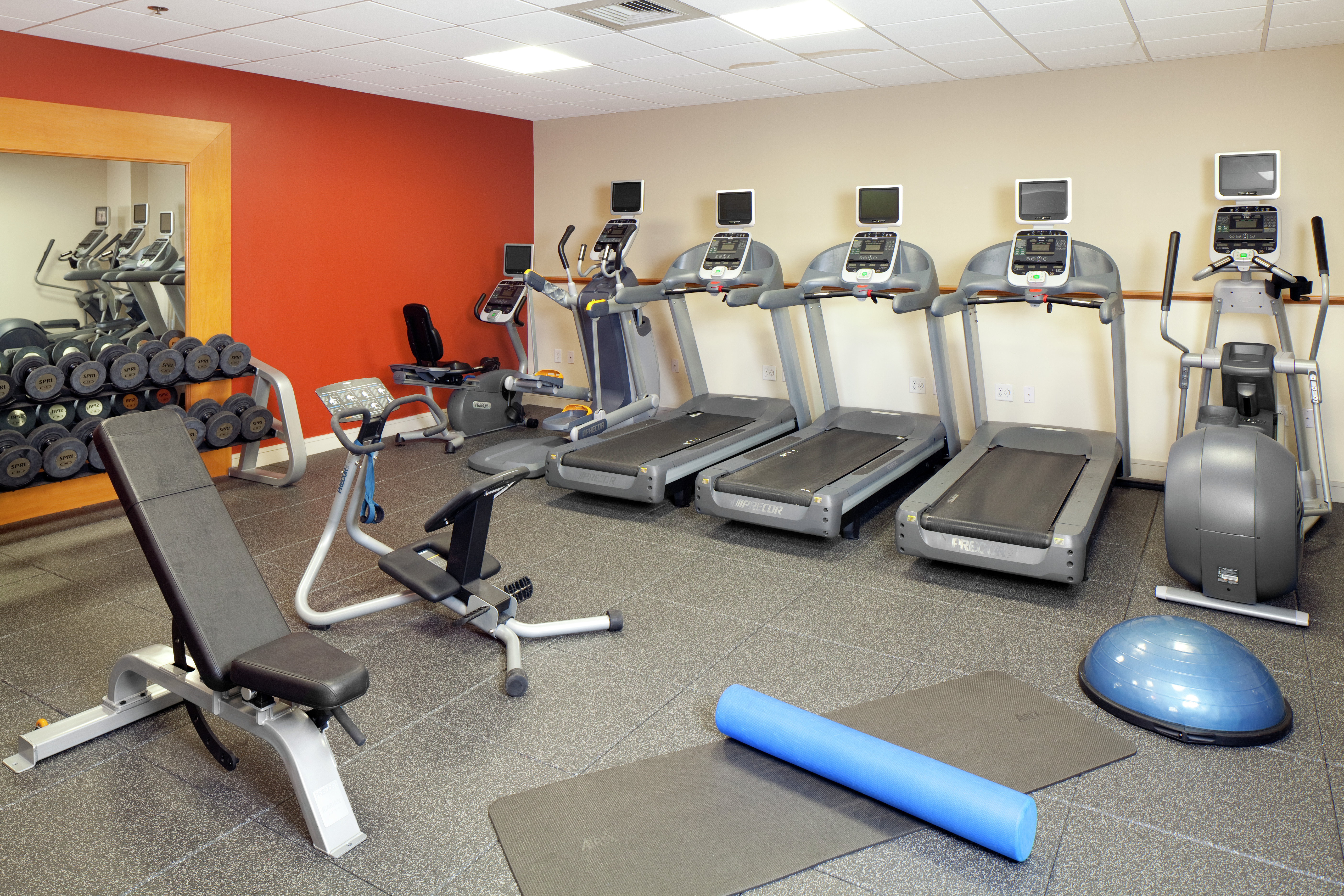 Fitness Center With Floor Mats, Weight Bench, Large Mirror, Free Weights, and Cardio Equipment