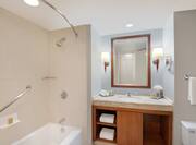 Guestroom Bathroom with Mirror, Vanity, Shower, and Bathtub