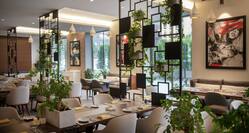 Gatsy Restaurant Dining Area with Tables, Chairs, Artwork, Plants, and Outside View