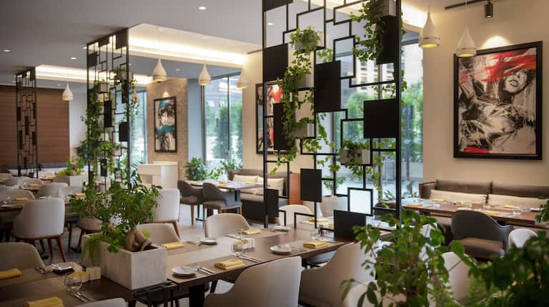 Gatsy Restaurant Dining Area with Tables, Chairs, Artwork, Plants, and Outside View