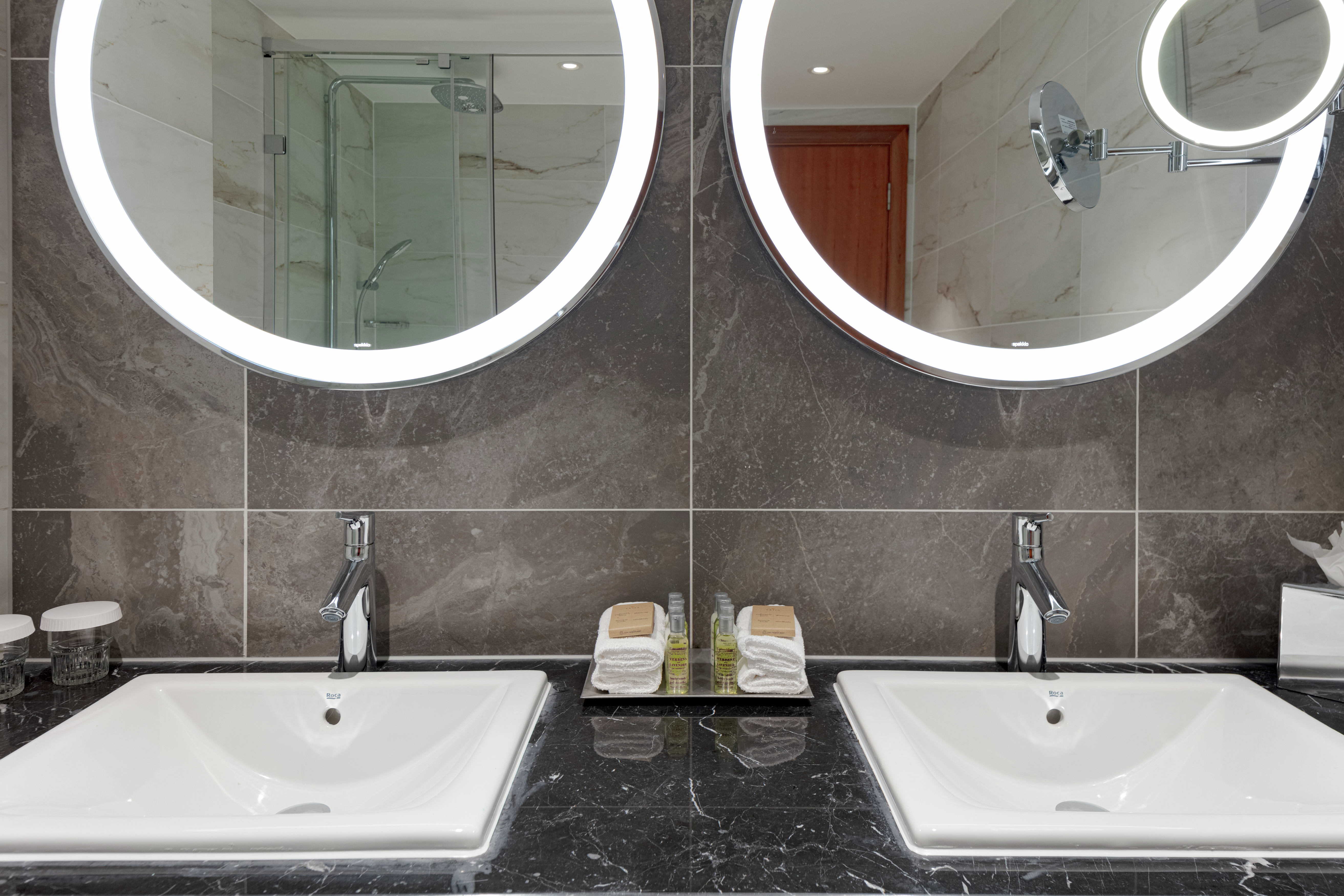 Dual Vanity Area with Two Round Lit Mirrors in Bathroom