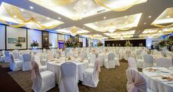 Ballroom With White Chairs, Place Settings, Flowers, and White Linens on Banquet Tables