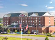Daytime View of Hotel Exterior, Signage, Flagpole, Landscaping, Circle Drive, and Parking Lot