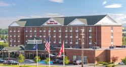 Daytime View of Hotel Exterior, Signage, Flagpole, Landscaping, Circle Drive, and Parking Lot