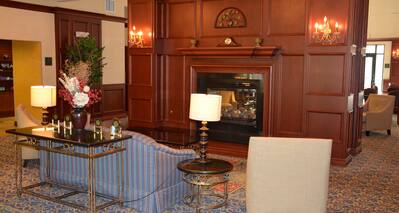 Two Armchairs, Sofa, and Tables With Illuminated Lamps Around Fireplace in Lobby Lounge Area