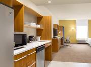 Guestroom Kitchen Area with Microwave, Fridge and Dishwasher with HDTV, Work Desk and King Bed in Background