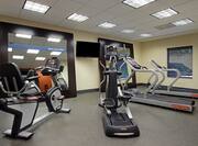Fitness Center With Cardio Equipment and TV Between Two Large Mirrors