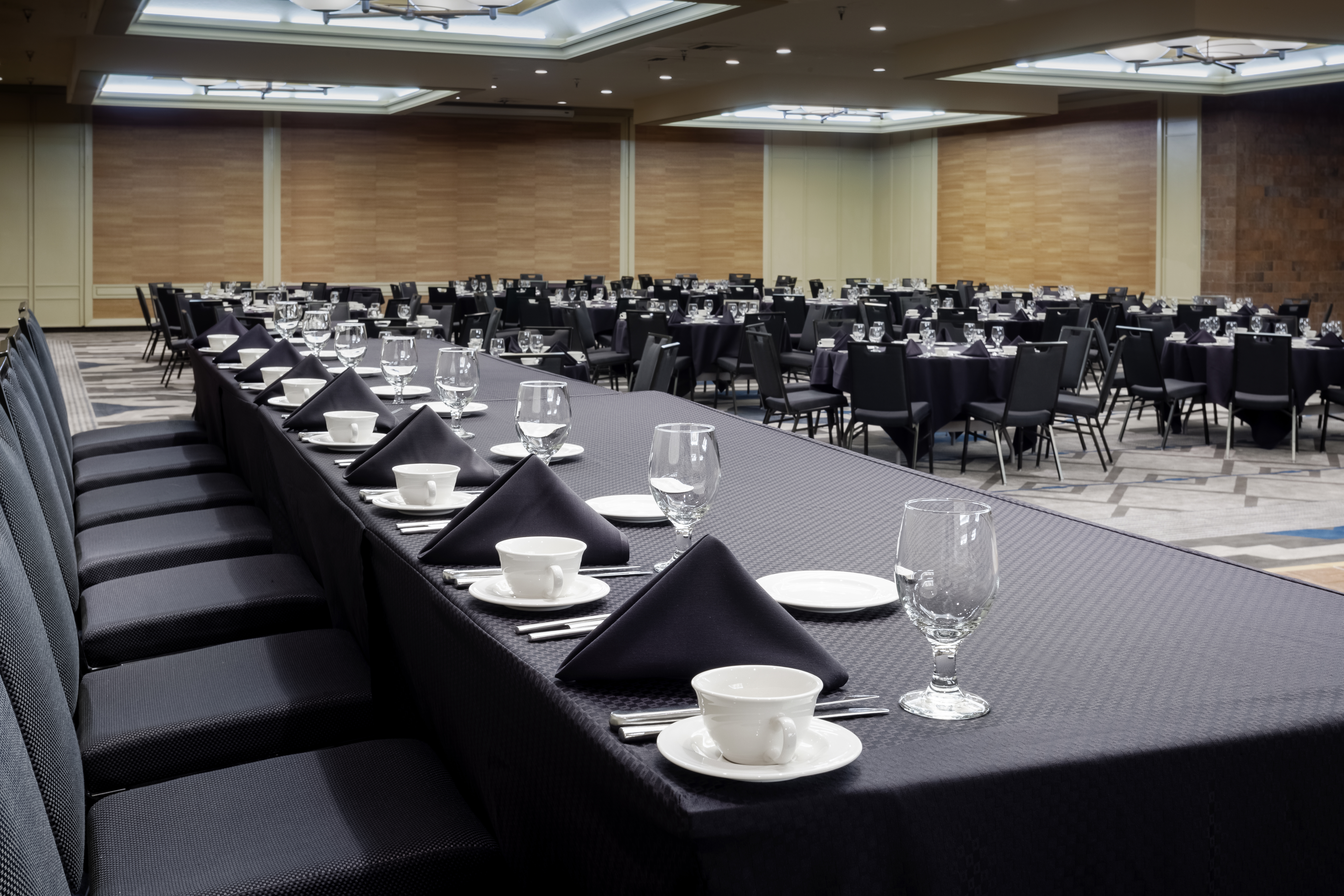 Detailed View of Place Settings on Conference Panel Table With Black Cloths and Round Tables in the Background