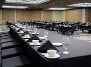 Detailed View of Place Settings on Conference Panel Table With Black Cloths and Round Tables in the Background