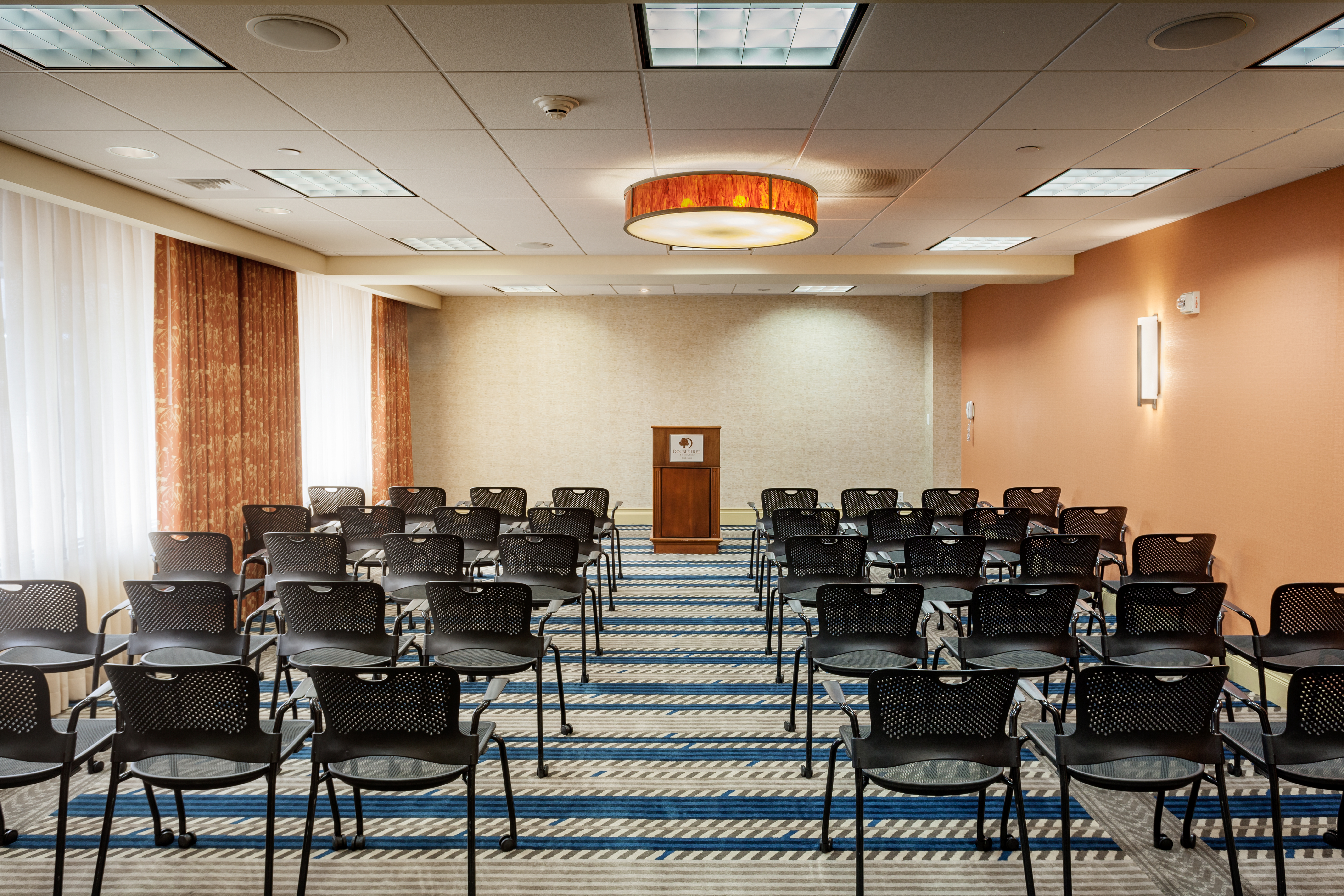 Meeting Room Set Up Theater Style With Rows of Black Chairs Facing Podium