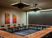 Meeting Room With Audio Visual Equipment Above Black Chairs Around Hollow Square Table and Wall Art 