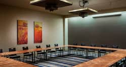 Meeting Room With Audio Visual Equipment Above Black Chairs Around Hollow Square Table and Wall Art 