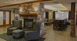 Lobby dining area with high-top table, high chairs, soft chairs, ottoman, and fireplace