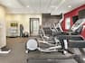 Spacious fitness center featuring cardio machines, scale, free weights, medicine balls, water dispenser, and complimentary towels.