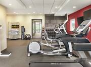 Spacious fitness center featuring cardio machines, scale, free weights, medicine balls, water dispenser, and complimentary towels.