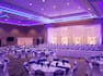 Wedding Reception Setup in Meeting Room With Purple and White Lighting, Place Settings, Flowers, and Purple Decor on Tables With White Linens