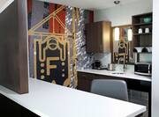 Suite Kitchen With Work Desk, Wall Mural, Drinkware in Wood Cabinets, Mirror Above Sink, Microwave, and Mini Fridge