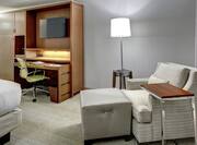 Bed, TV, Work Desk, Illuminated Floor Lamp, and Reading Chair in Guest Room