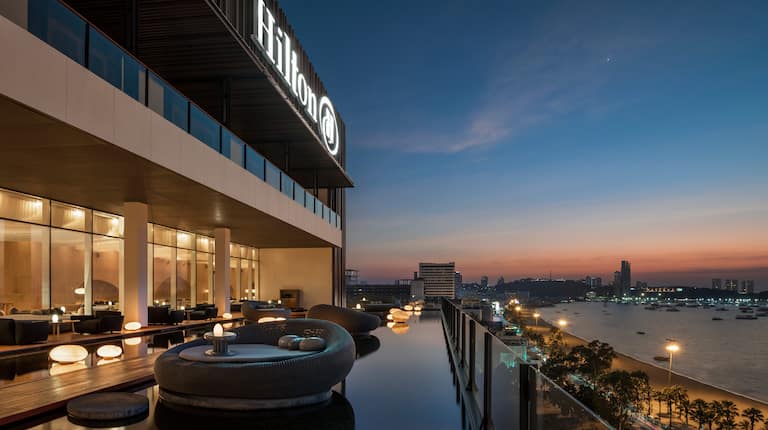 Terrasse der Lobby Lounge und Bar „Drift“ mit Blick auf die Bucht bei Sonnenuntergang