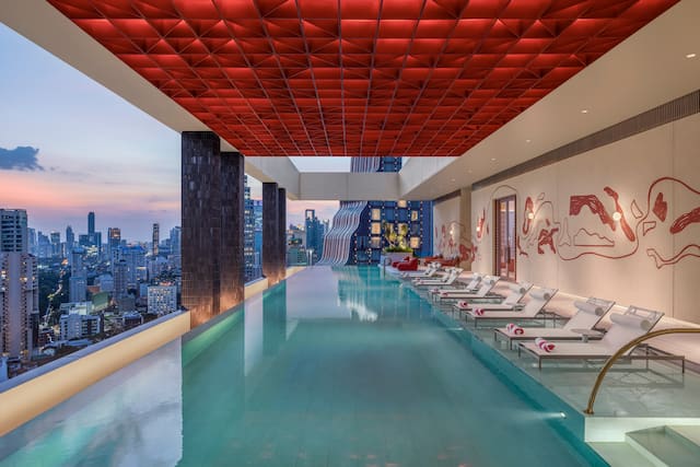 Outdoor pool with loungers, towels and city view