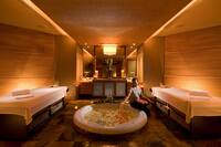 Spa Treatment Room with Two Massage Beds and Woman Sitting Next to Tub 