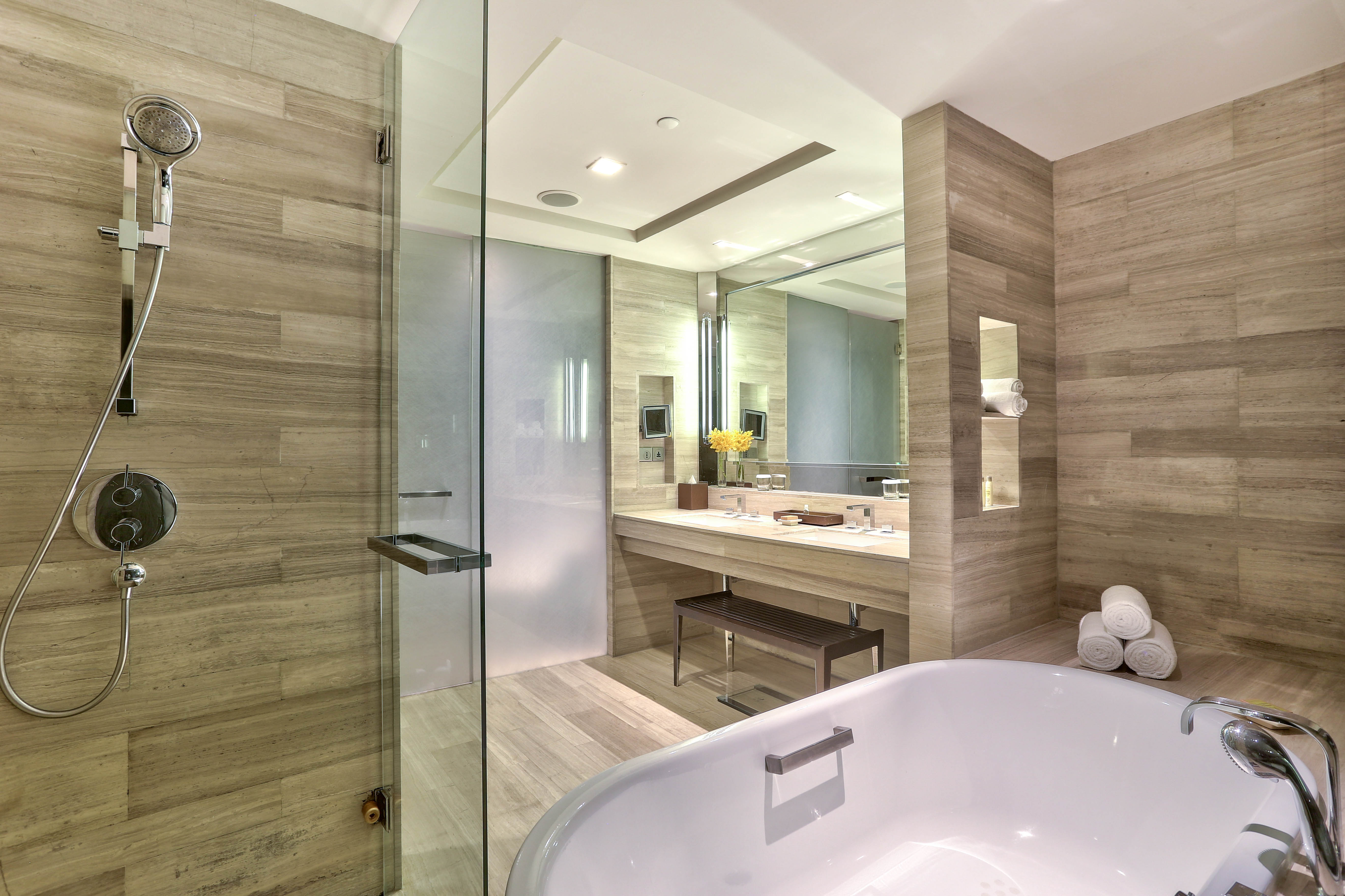 Junior suite bathroom tub, shower, vanity mirror, sink, bench, and towels