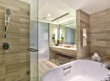 Junior suite bathroom tub, shower, vanity mirror, sink, bench, and towels