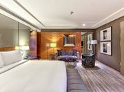Presidential suite with king bed, footrest, and lounge area with sofa and soft chair