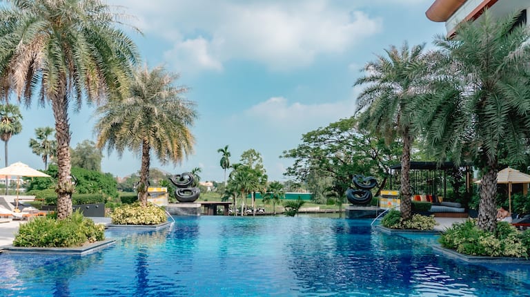 Outdoor pool with surrounding trees and statues