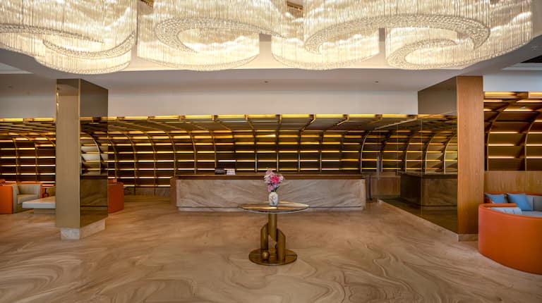 Lobby area with front desk, table and chandeliers