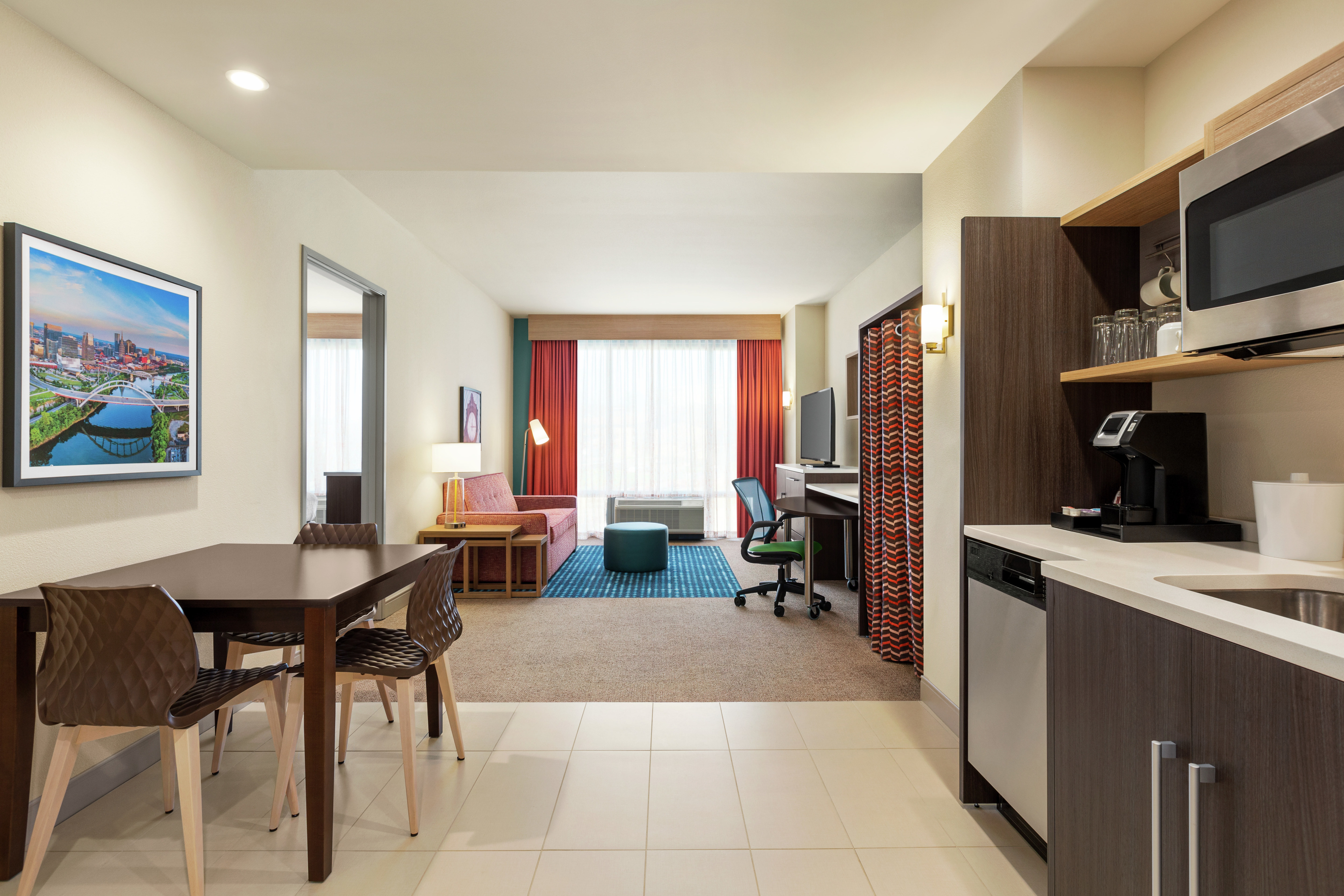 Spacious living area in suite featuring fully equipped kitchen, dining area, and lounge with sofa.