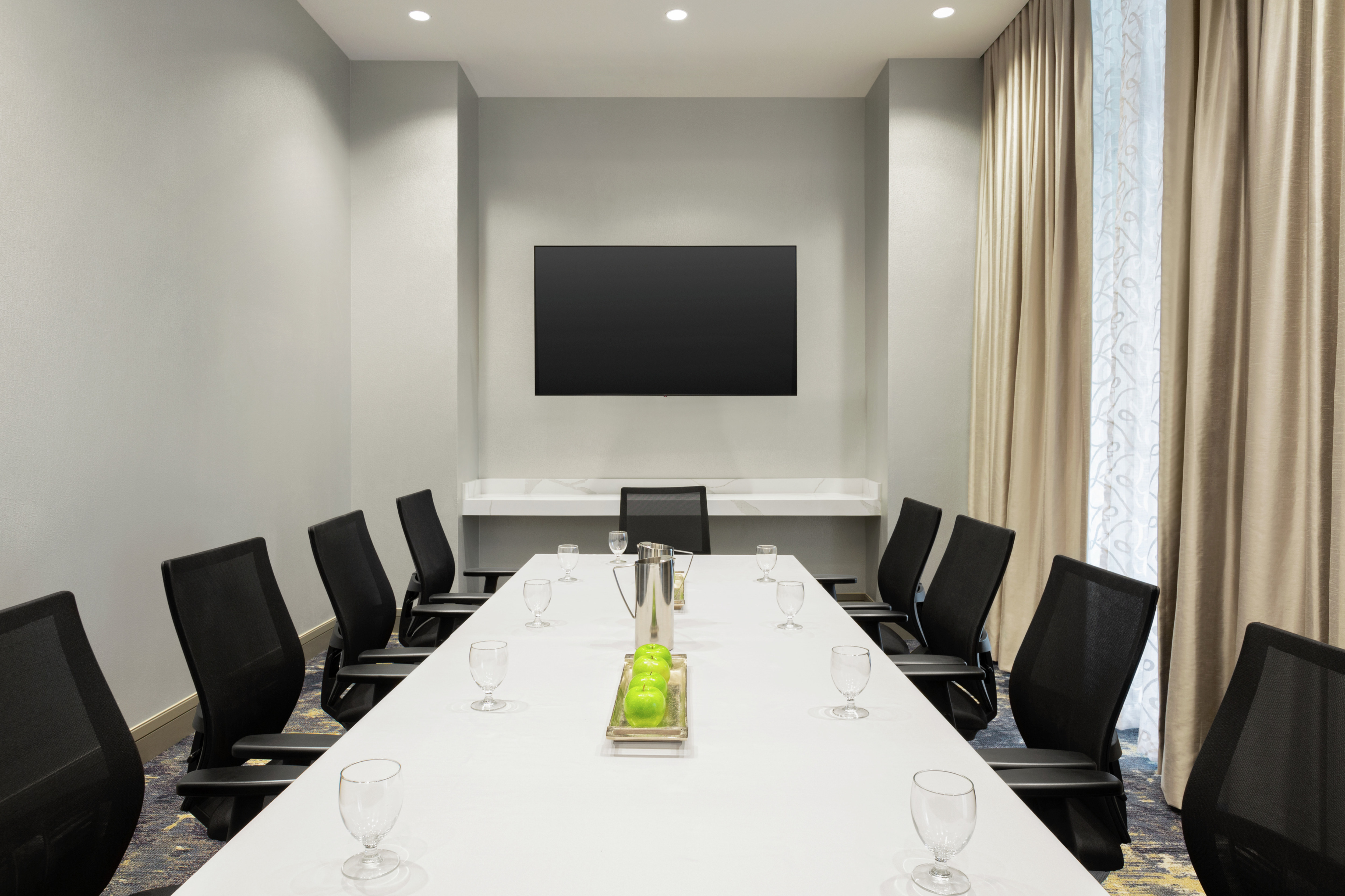 Bright on-site meeting room featuring large boardroom table and TV at front of room.