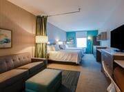 Overview of suite with twin queen beds, lounge area with sofa, television and work desk