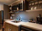 Guest room kitchenette with sink, cups, glasses and mini oven