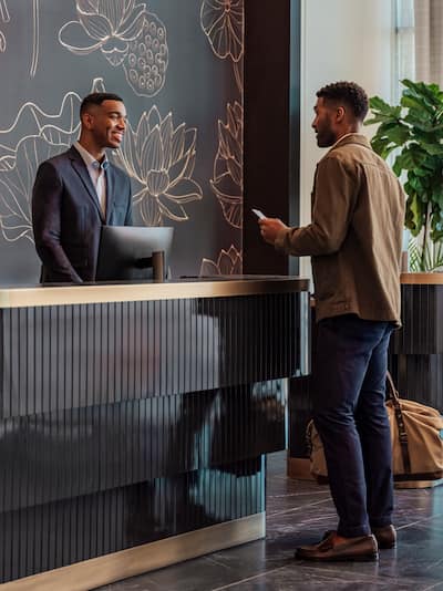 Un homme à la réception accueilli par le personnel de la réception