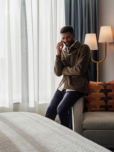 Un homme dans une chambre discutant au téléphone, assis sur une chaise