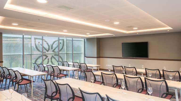 Sala de reuniones con montaje tipo aula y televisor de alta definición montado en la pared