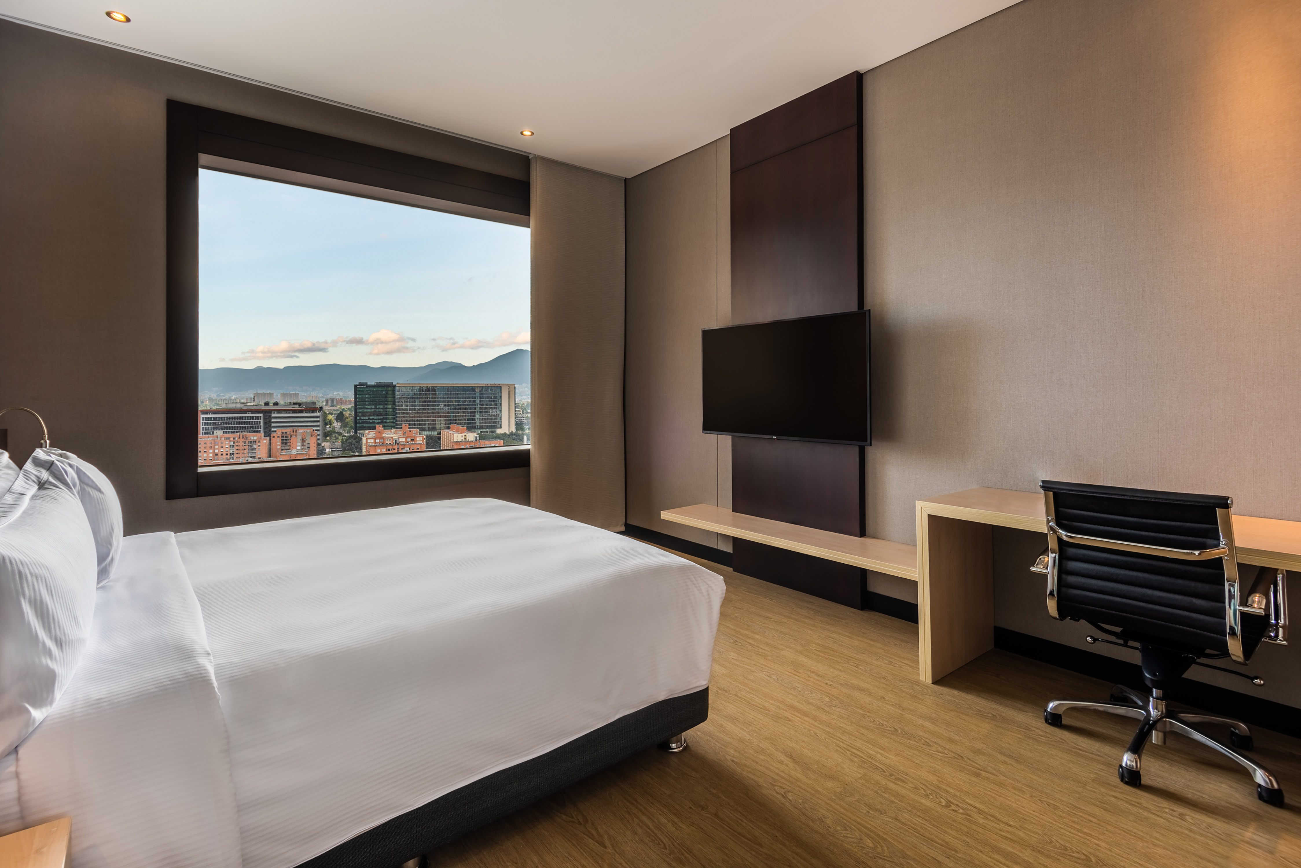 Bed in Guest Room with Desk HDTV and City View