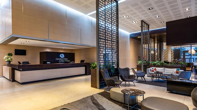 Recepción del hotel DoubleTree by Hilton y sala de estar del lobby con televisor de alta definición