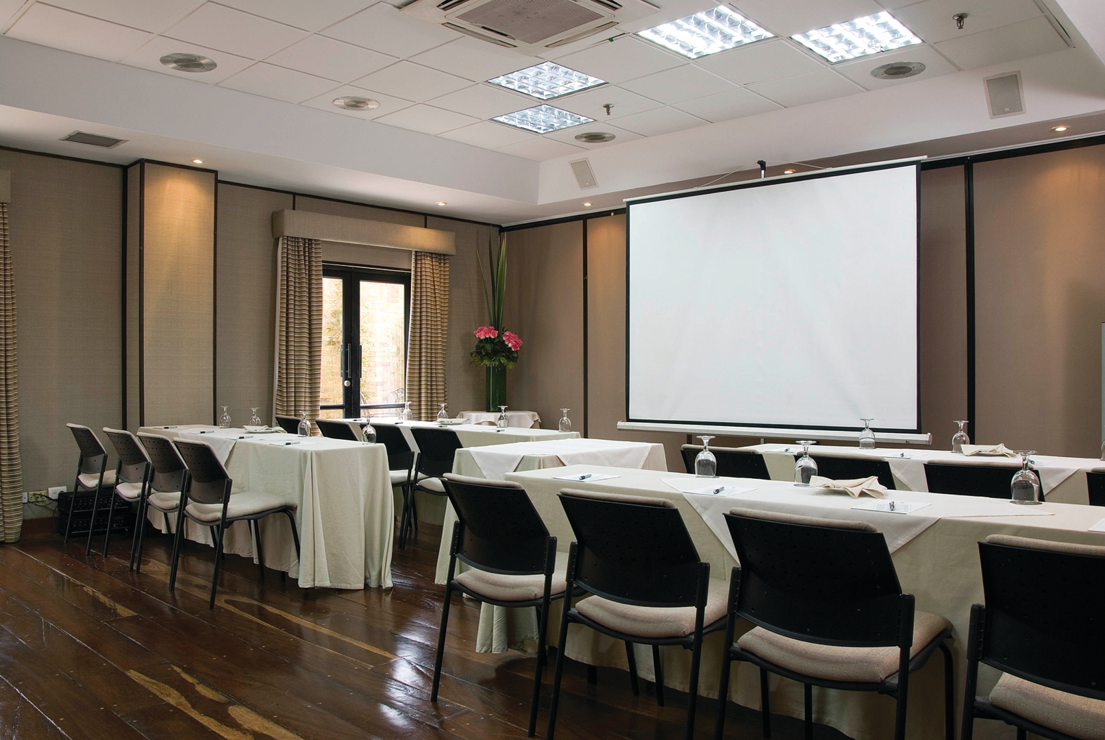 Sala de reuniones pequeña con mesas y sillas frente al proyector