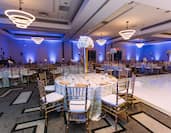 Wedding ballroom with full dining tables setup and partial view of dance floor