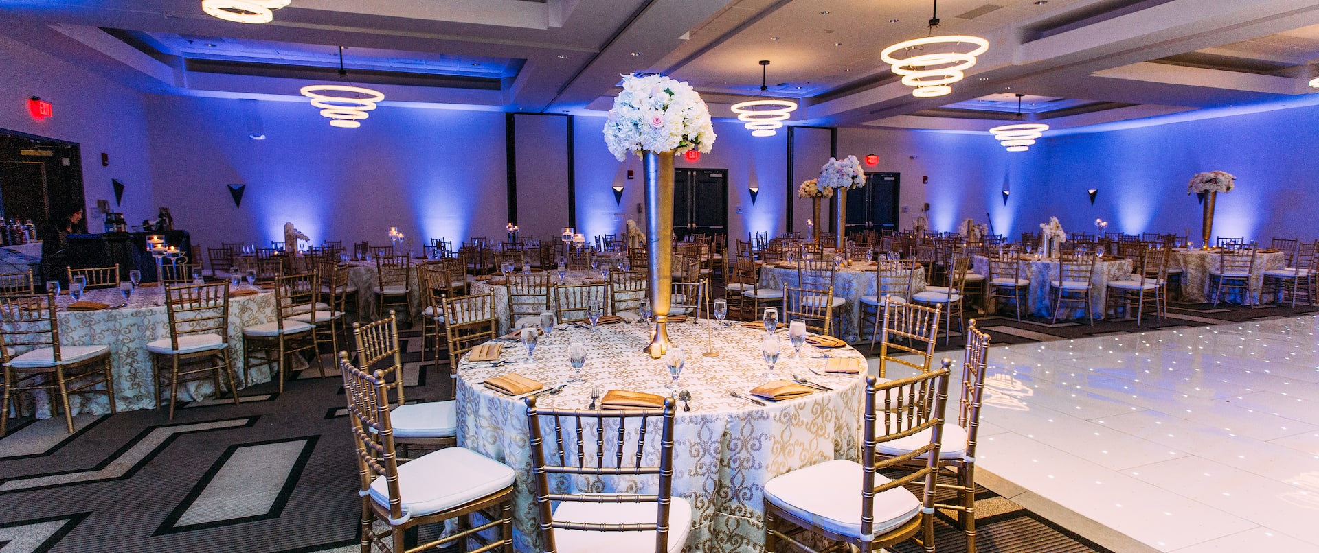 Wedding ballroom with full dining tables setup and partial view of dance floor