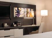Media Center With TV, Coffee Maker, Monitor Above Work Desk With Illuminated Lamps and Internet Outlets in Guest Room 