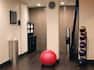Fitness Center With Towel Station, Wall Clock, Red Exercise Ball, Water Cooler, Large Mirror, and Weight Balls